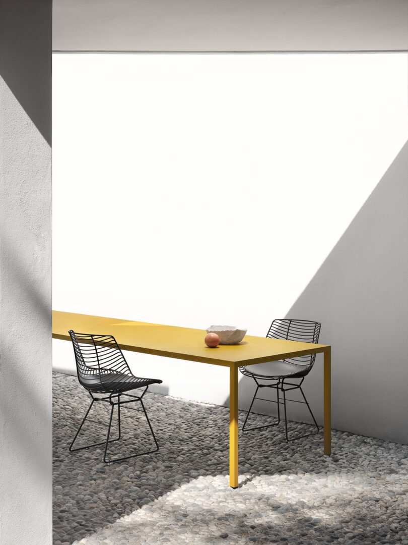 Yellow rectangular outdoor table and black chairs.