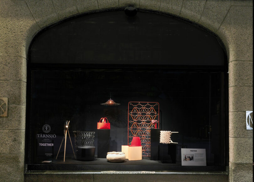 A dimly lit store display window showcasing an eclectic collection of NK Interior's designer home furnishings.