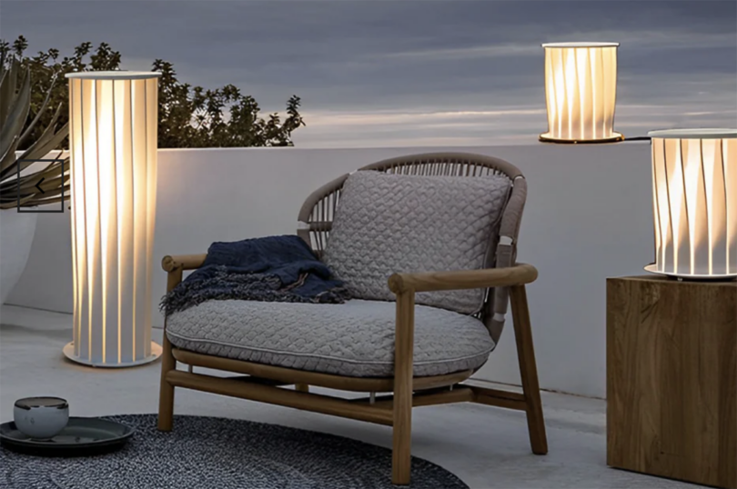 Modern outdoor furniture and elegant floor lamps on a terrace at dusk.