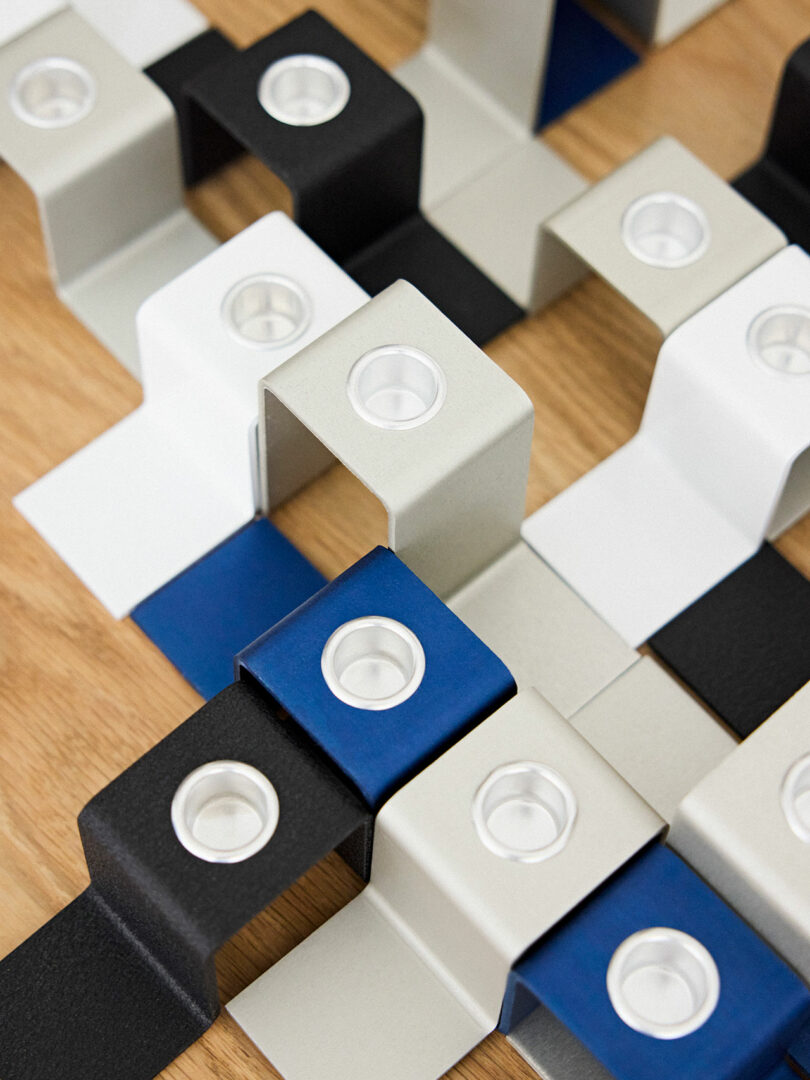 Overhead view of interconnected magnetic blocks in black, blue, white, and gray arranged on a wooden surface.