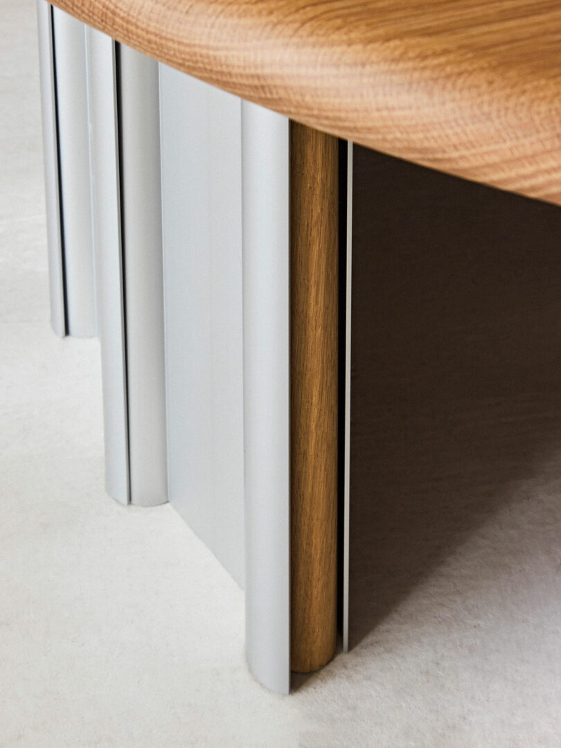 Close-up of a wooden table corner with white metal legs on a beige carpet.
