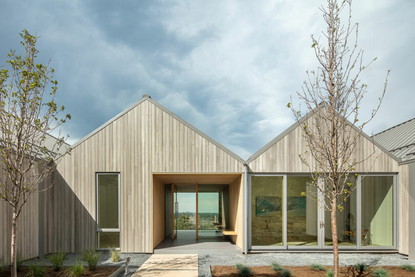 closeup partial view of modern home exterior clad in light wood with pitched roof line.