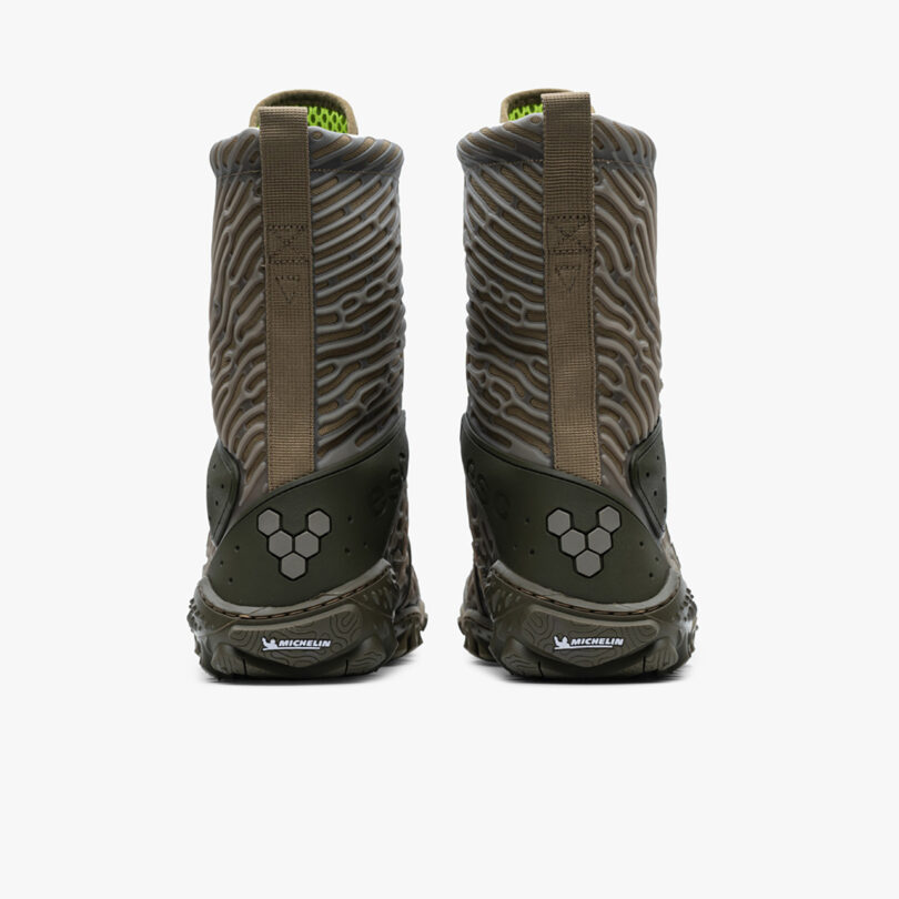 A pair of green and brown Vivobarefoot Jungle ESC boots with distinctive Michelin sole patterns, viewed from the back.