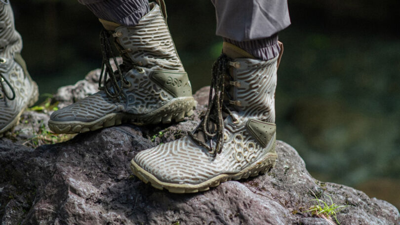Close-up of Vivobarefoot Jungle ESC boots on a rock, highlighting their rugged treads and secure lacing.