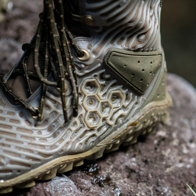 Close-up of a rugged Vivobarefoot Jungle ESC boot with detailed tread pattern on a rocky surface.