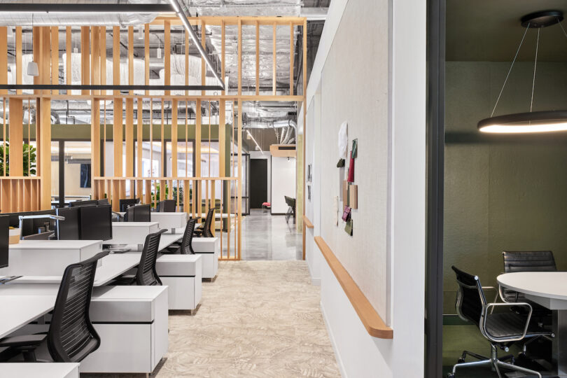 Modern office interior with cubicles, ergonomic chairs, and wooden partitions, featuring an open ceiling and stylish, minimalistic decor