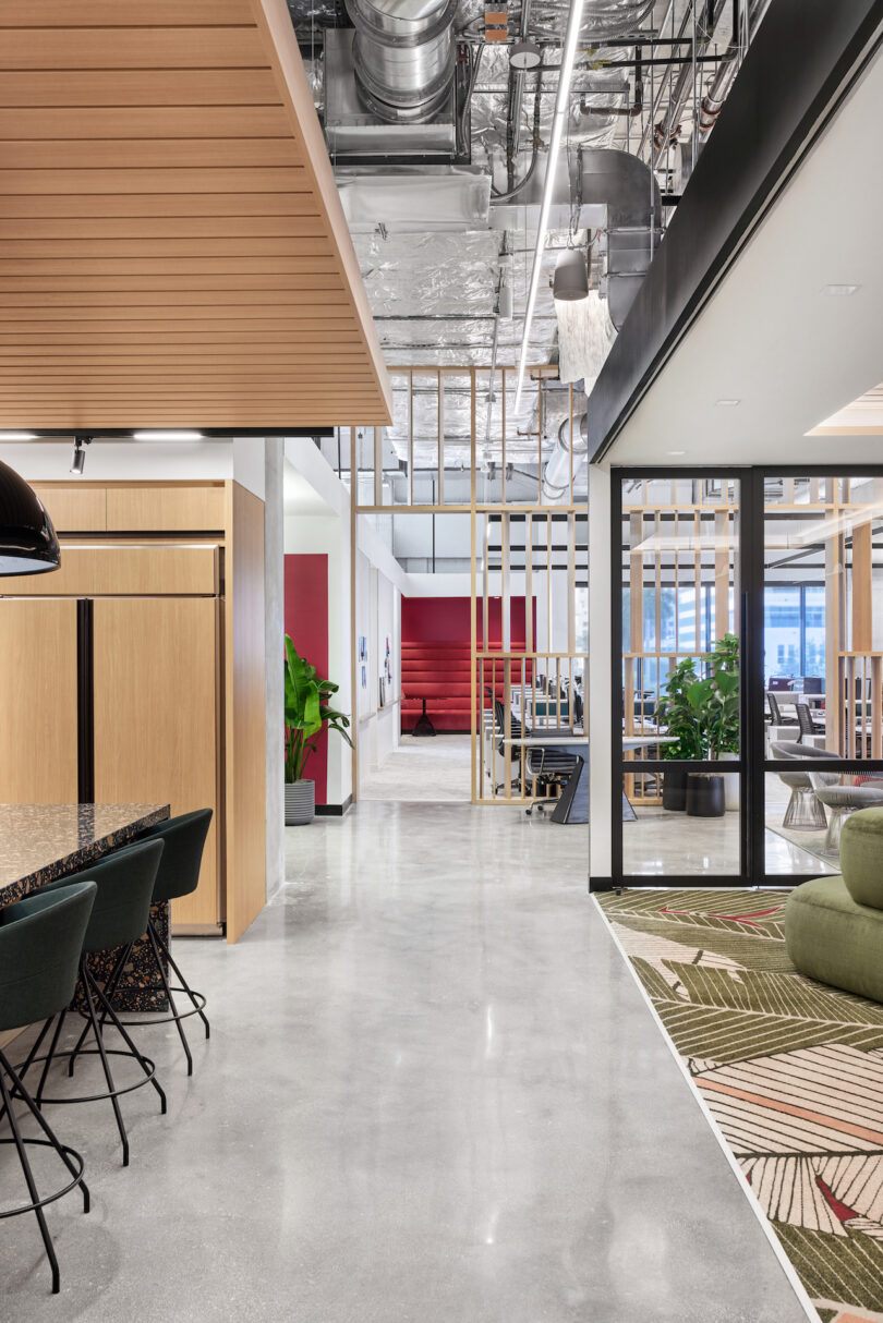 Modern office space featuring a sleek interior with exposed ceilings, wooden accents, and vibrant partitions, decorated with plants and stylish furniture