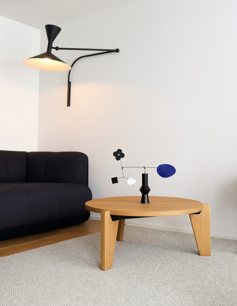 a desktop mobile with various shapes and a black base on a wooden coffee table next to a sofa