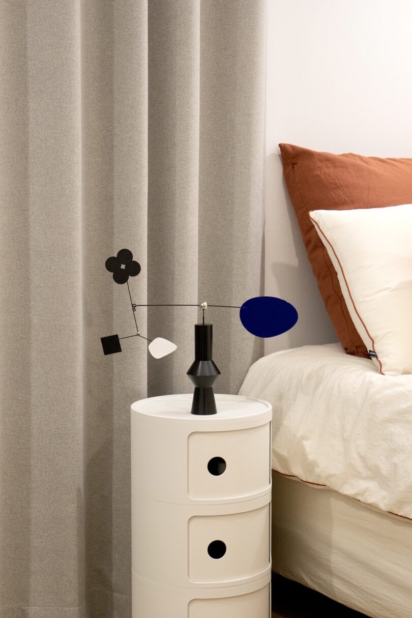 a desktop mobile with various shapes and a black base on a white round table next to a bed
