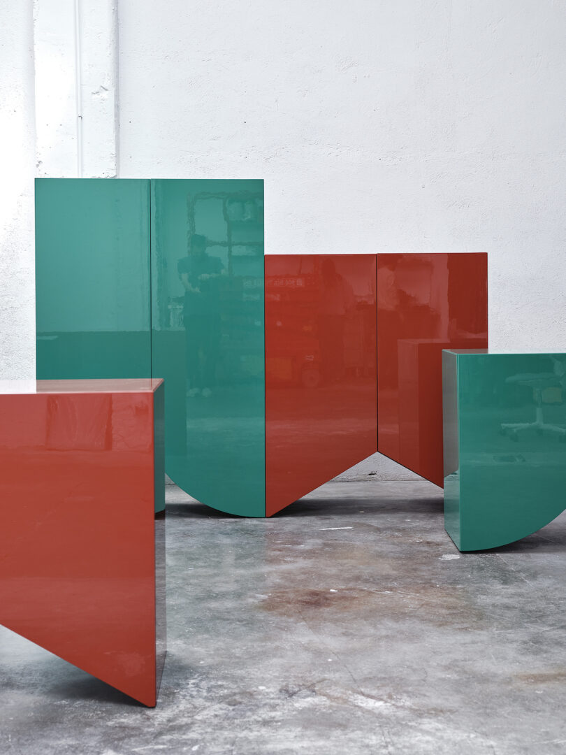 two green cabinets and two red cabinets with bases shaped like bridges on a concrete floor