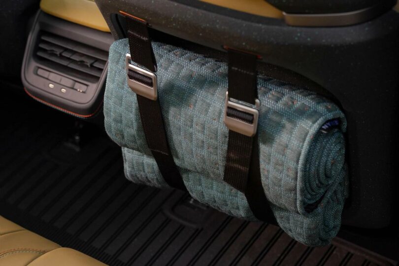 back of passenger seat in a car with a blanket rolled and strapped in