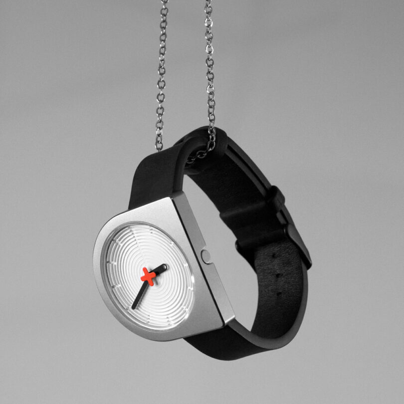 A modern D-shaped wristwatch with a black strap and silver case, hanging by a chain, displayed against a gray background.