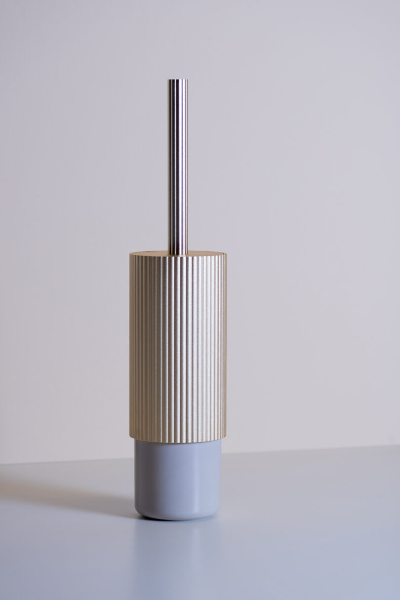 a toilet brush holder on a grey shelf