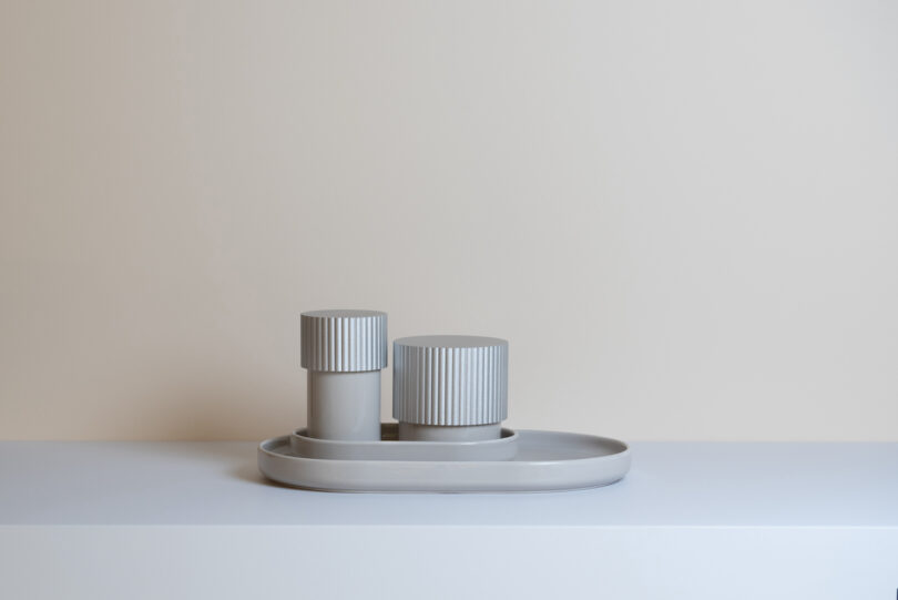 two metal storage boxes on a tray on a grey shelf