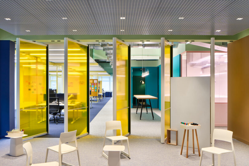 Modern office space with colorful glass partitions and collaborative areas.