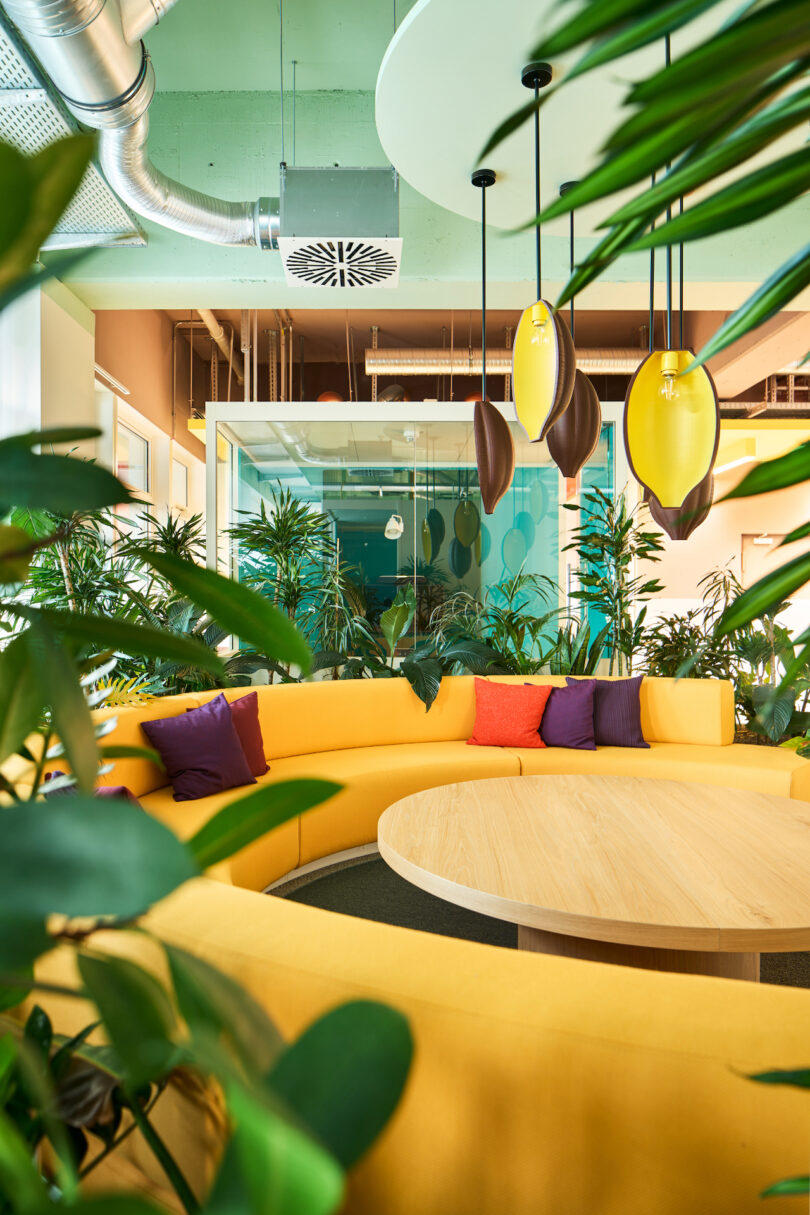 Modern office lounge area with vibrant yellow seating and lush green plants.