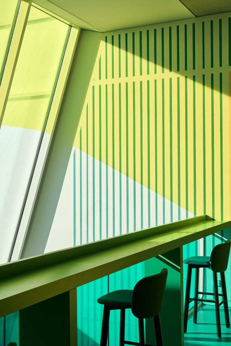 Modern interior with geometric shadows and green chairs.