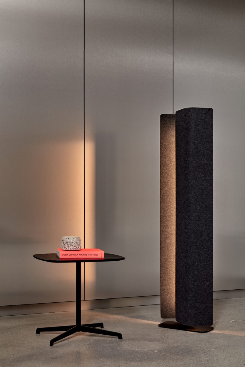 standing pendant light next to a black table with a book on top