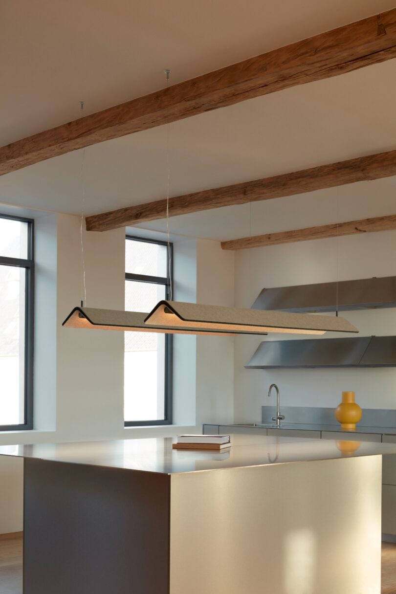 two felt pendant lights over a kitchen island with books on top