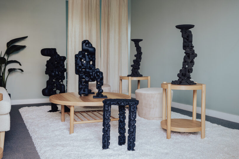 Modern living room featuring abstract black sculptures on wooden tables, a plush white rug, and minimalistic decor