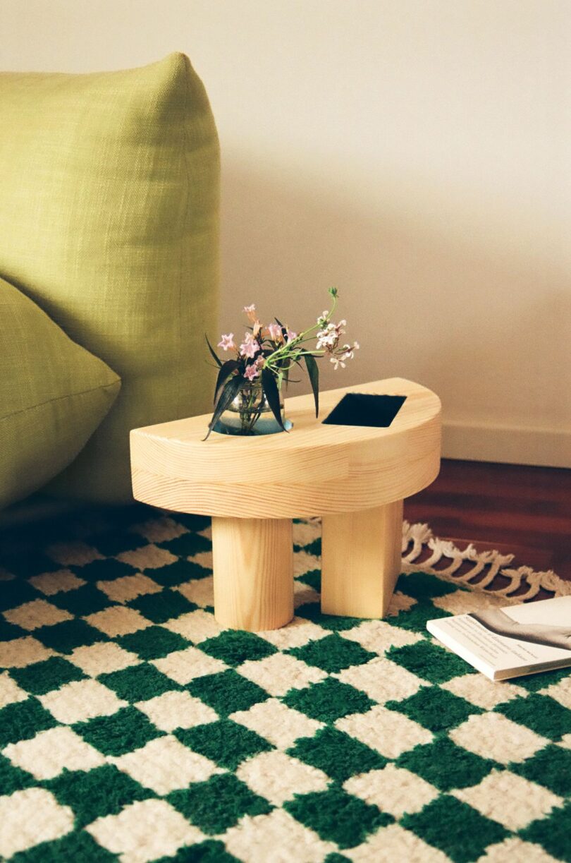 wood side table with colorful geometric cut outs on a green and white checkered rug