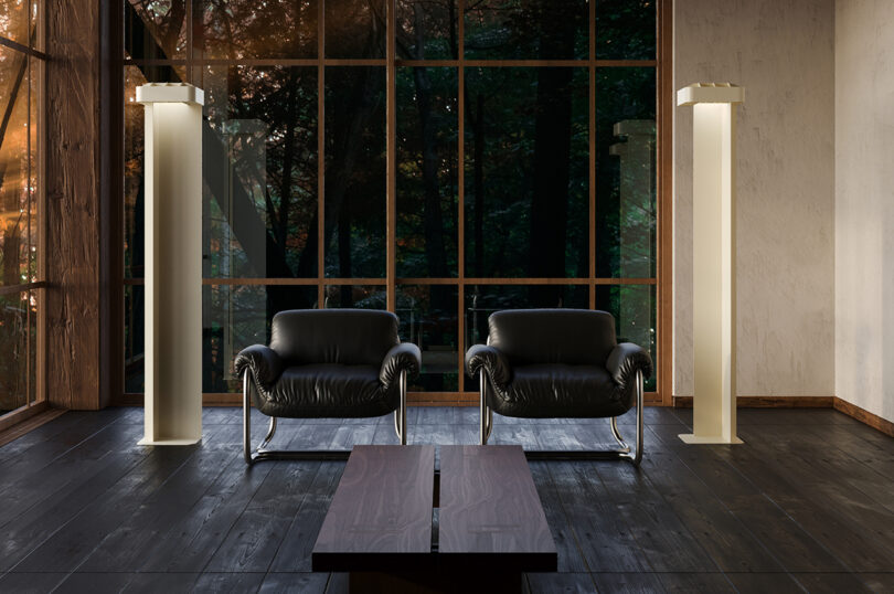 Um quarto moderno com duas cadeiras de couro preto, duas luminárias altas brancas, uma mesa de centro e janelas grandes.