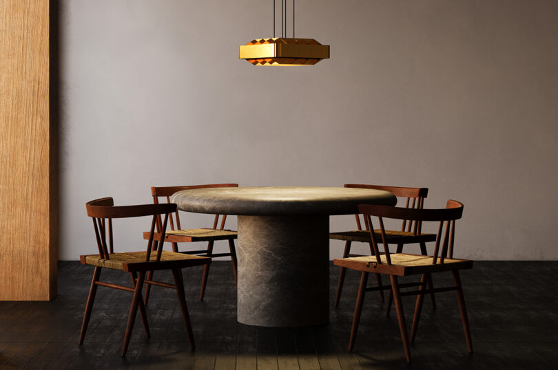 Sala de jantar moderna com mesa redonda, quatro cadeiras de madeira, piso de madeira escura e luminária pendente geométrica.