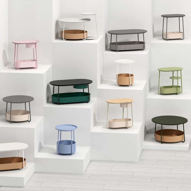 A collection of modern coffee tables in various colors displayed on white shelving units