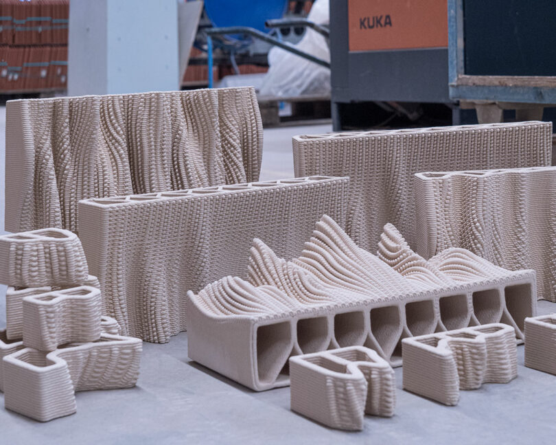 3d printed ceramic objects with intricate designs displayed in a workshop environment.