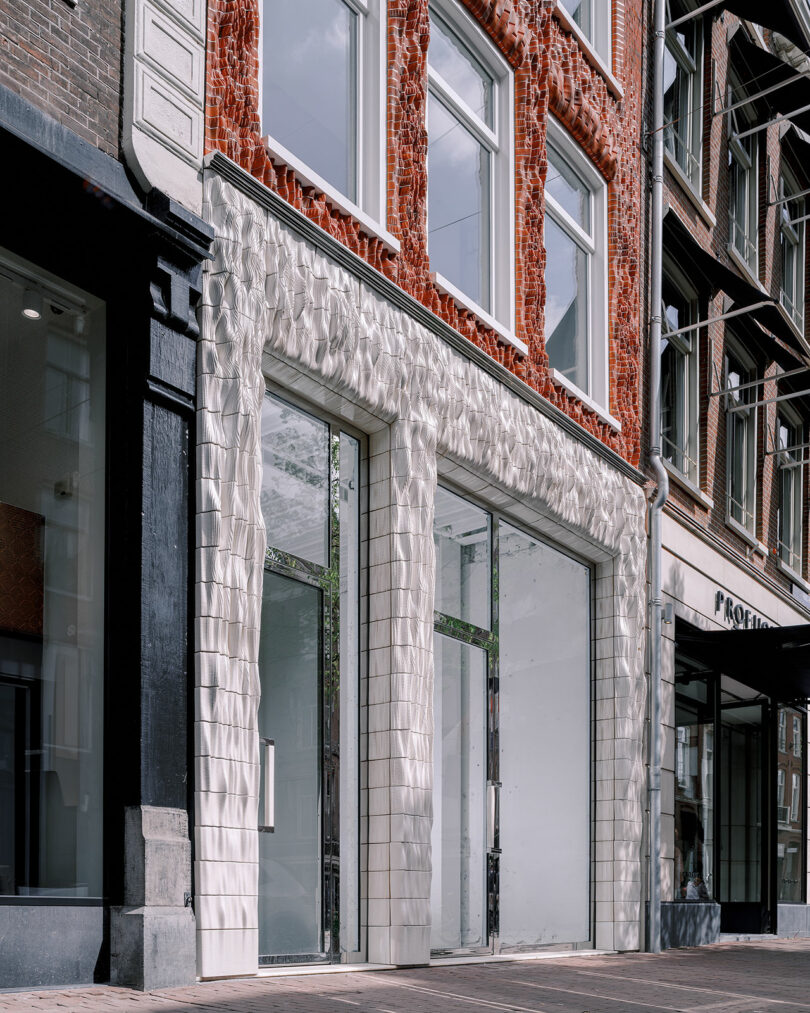An ornately tiled storefront exterior with two large glass windows, located in a brick building on a city street.