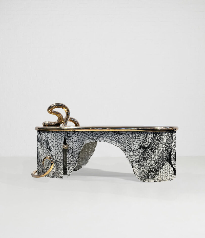 A unique, sculptural table with a Design Miami-inspired snake design and textured surface, featuring metallic accents and a smooth top.