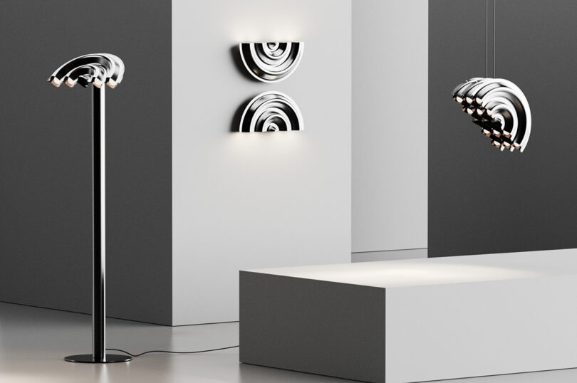 Uma configuração interior com uma luminária de chão cromada, duas luminárias semicirculares montadas na parede e uma luminária semicircular suspensa, com paredes minimalistas em preto e branco e uma plataforma retangular branca.
