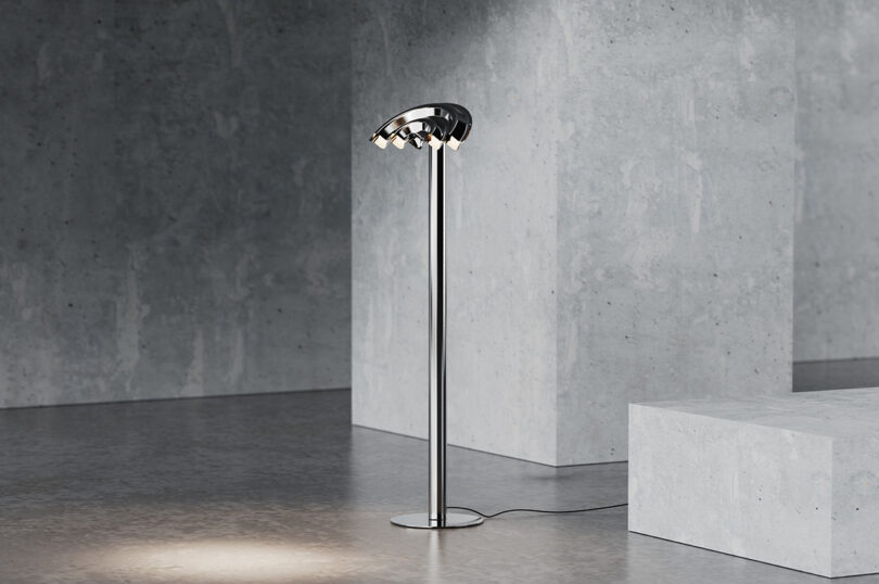 A modern floor lamp with a sleek metallic design and dome-shaped shade stands on a concrete floor.