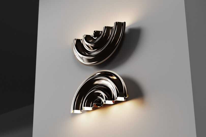 Two modern, metallic wall sconces with curved, layered designs are mounted on a gray wall, emitting a warm light.
