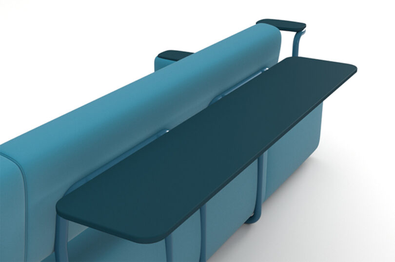 A modular blue modern sofa with a backrest that extends to form a narrow horizontal surface behind it.