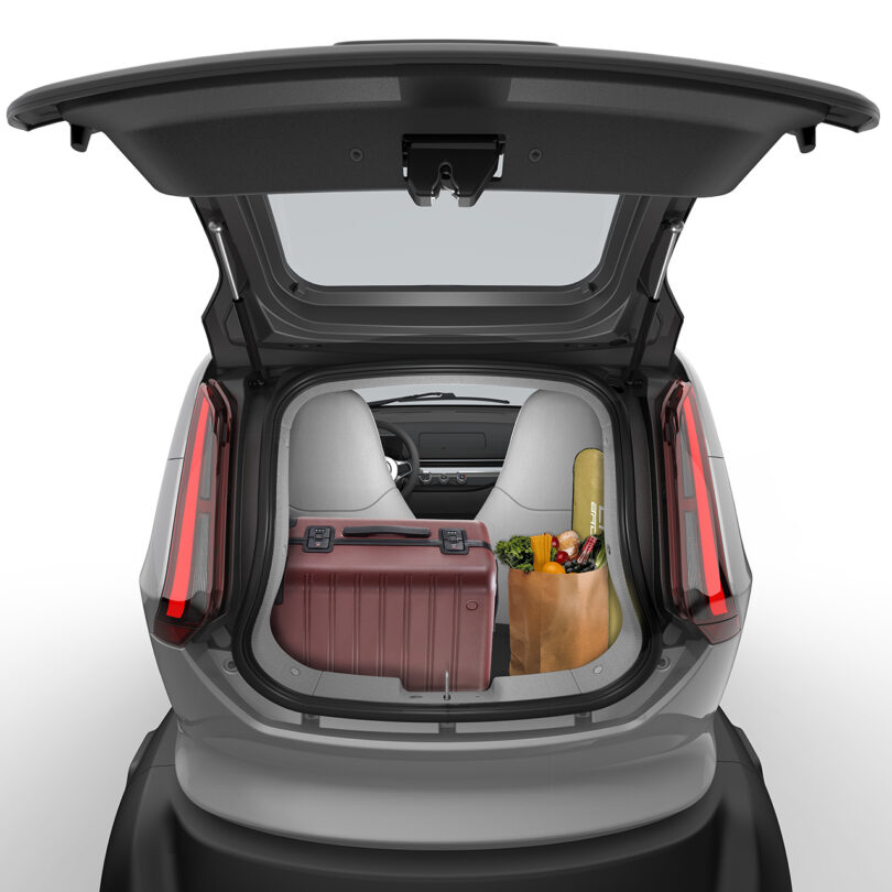 Open trunk of a modern micro EV, Eli ZERO, showing packed groceries and a suitcase, viewed from the rear.