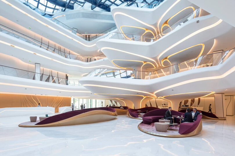 Interior of a modern building with organic, curved white structures, elegant seating areas, and a spacious, light-filled atrium.