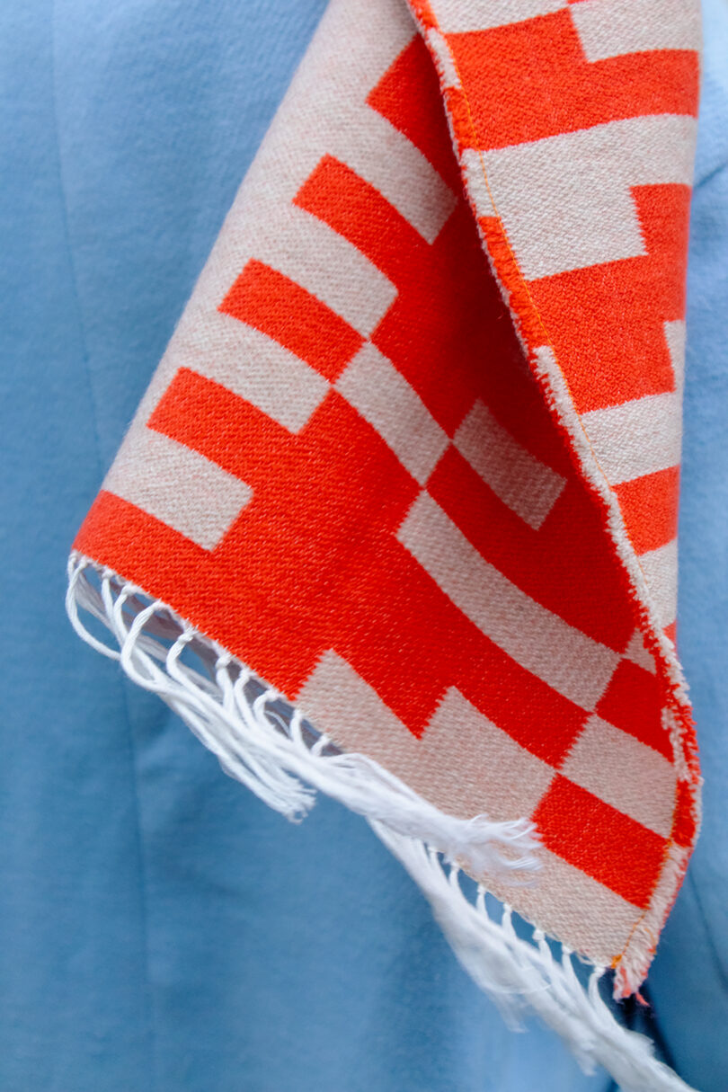 An orange and white patterned scarf with fringe detailing on its edge.