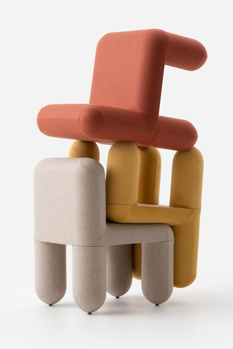 Three stacked modern chairs in beige, mustard, and rust colors.