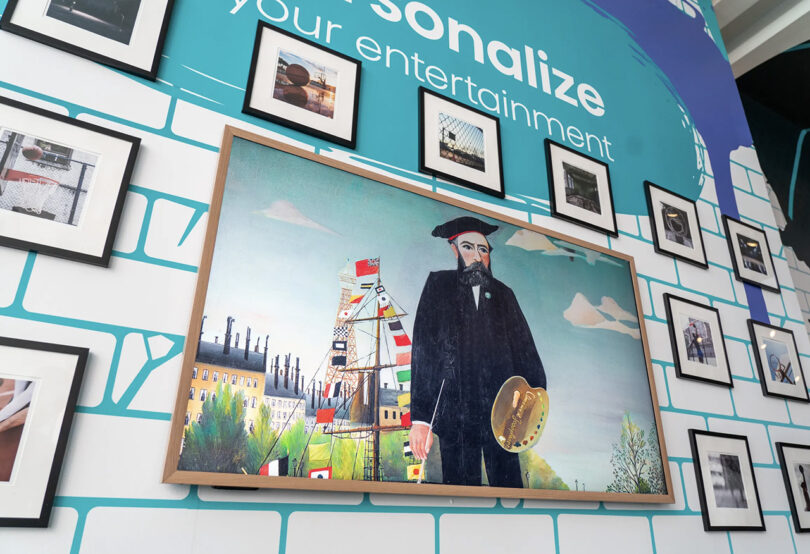 Large QLED 4K Hisense CanvasTV wall mounted on trade show wall display alongside framed pieces of artwork; traditional piece of art of Claude Monet displayed on the television.