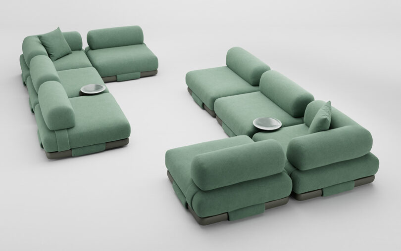Two modular green sofas, each with multiple sections and matching cushions, set on a light gray floor. Small round trays are placed on the sofas.