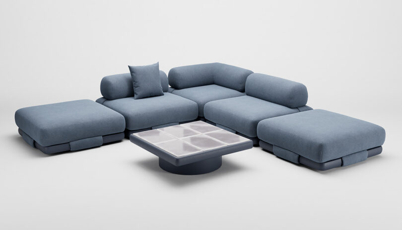 A modern sectional sofa with blue upholstery is arranged around a square coffee table with a grid-patterned surface.