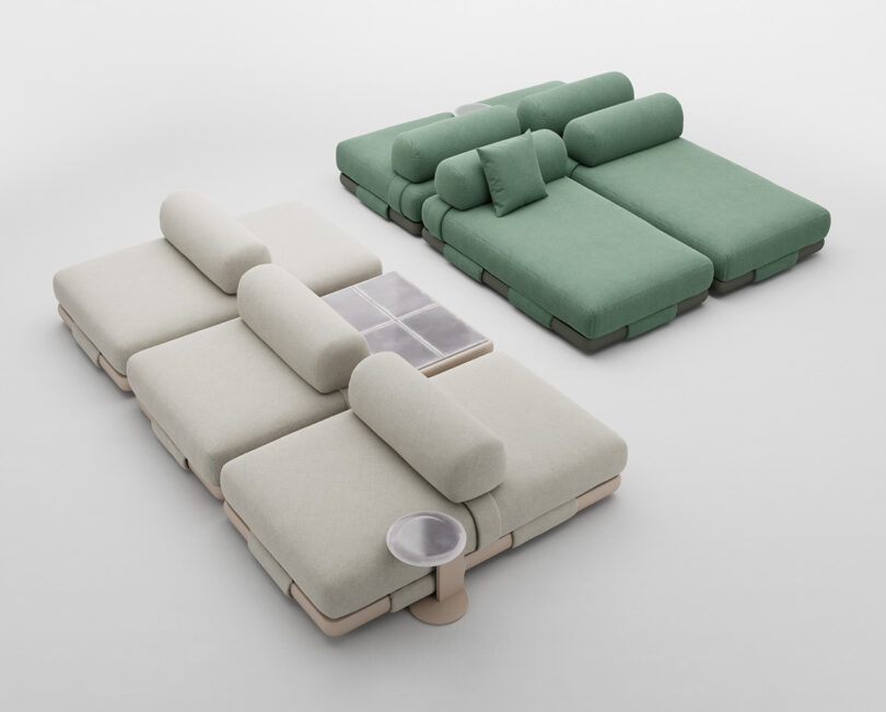 Two modern, modular sectional sofas in a minimalist setting. The foreground sofa is beige with rounded cushions and a built-in side table, while the background sofa is green with similar design elements.