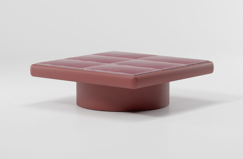 A square, maroon coffee table with a cylindrical base on a plain white background.