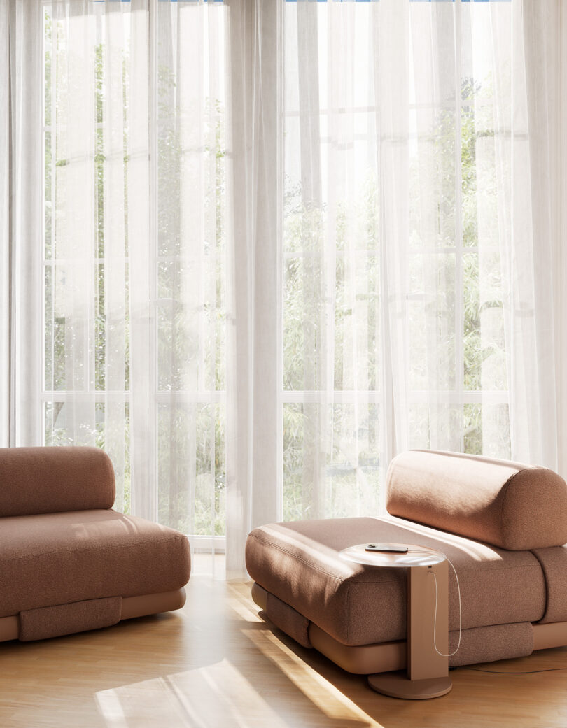 A sunlit room with sheer white curtains, featuring a brown modular sofa, an ottoman, and a side table.