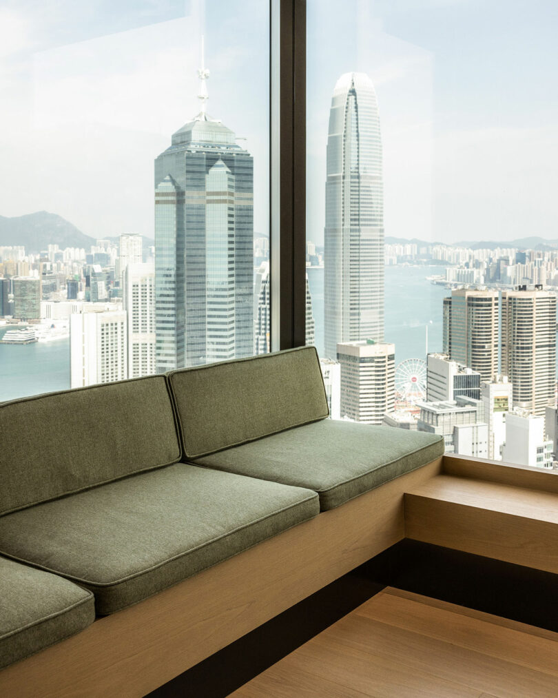 corner apartment interior view of built-in sofa with light green cushions looking out to views of Hong Kong
