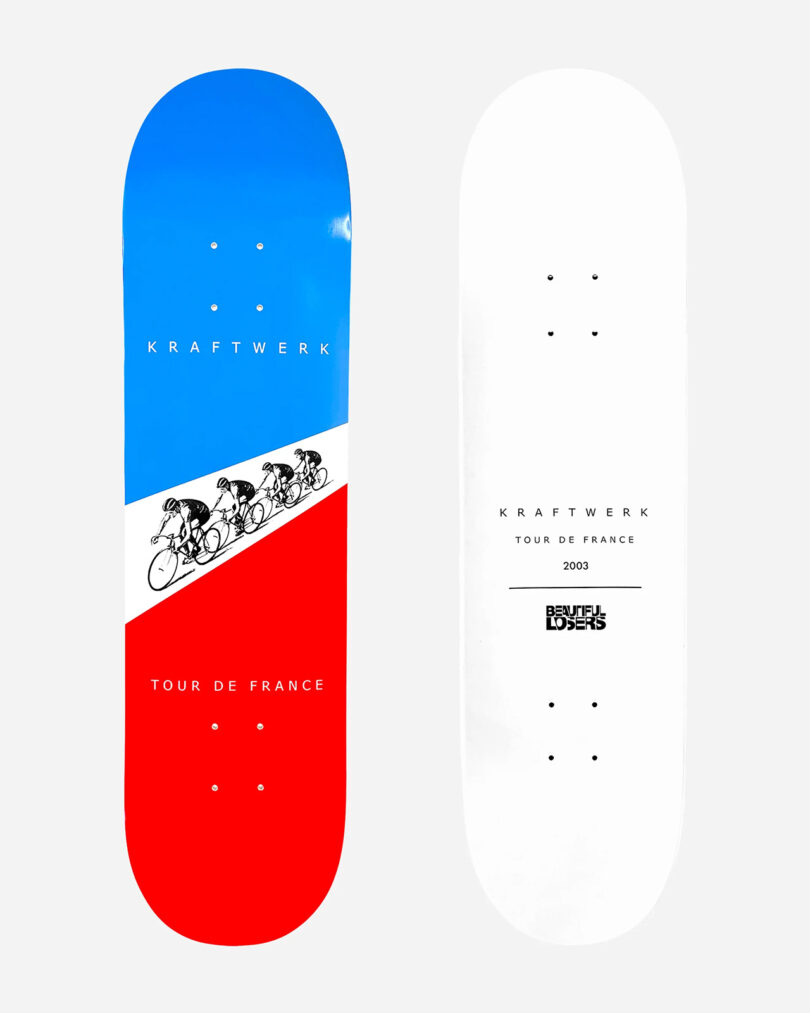 Two skateboard decks shown side by side. The left deck features a design with cyclists on a red, white, and blue background while the right deck is plain white with black text detailing "Kraftwerk Tour de France 2003". This pair is part of the exclusive Kraftwerk Collection Skateboard Decks.