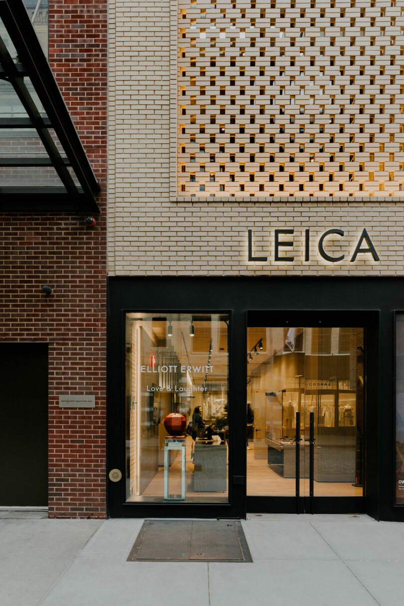 Exterior view of a leica camera store with a brick façade, displaying the elliott erwitt exhibition sign at the entrance.