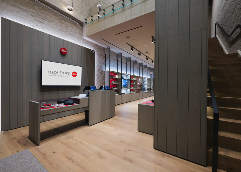 Interior of a leica store showcasing cameras and accessories on display shelves, with prominent branding and modern wooden decor.