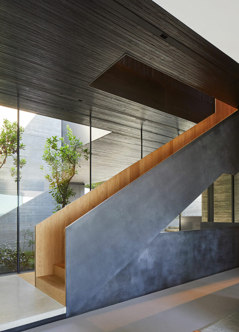 Angled view of modern home interior with a black metal staircase and black wood ceiling.
